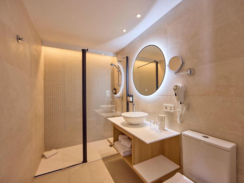 Bagno moderno con specchio rotondo, lavabo su piano e doccia aperta.