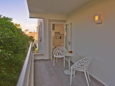 Balkon met twee witte stoelen en een kleine tafel, omgeven door planten.
