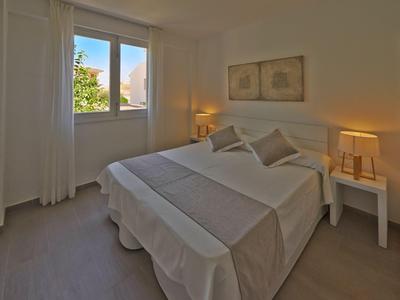 Licht ingericht hotelkamer met een tweepersoonsbed en zachte gordijnen bij een raam.