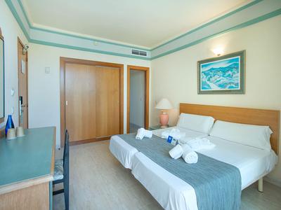 Lichte hotelkamer met tweepersoonsbed, houten meubels en een schilderij aan de muur.