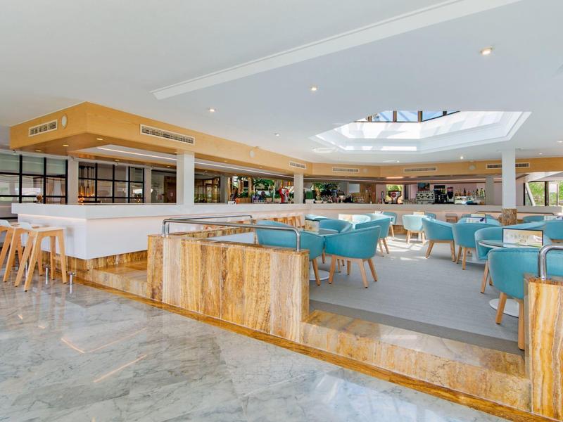 Großer, moderner Speisesaal mit blauen Stühlen, Holzdetails und hellem Marmorfußboden.