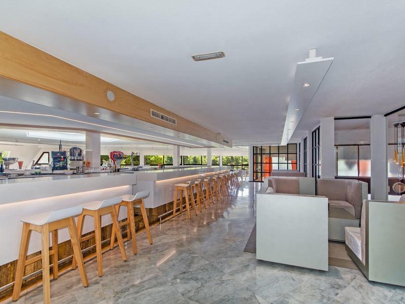 Moderner Gastraum mit langen Theken, Holzstühlen und hellen Sitzecken aus Leder.