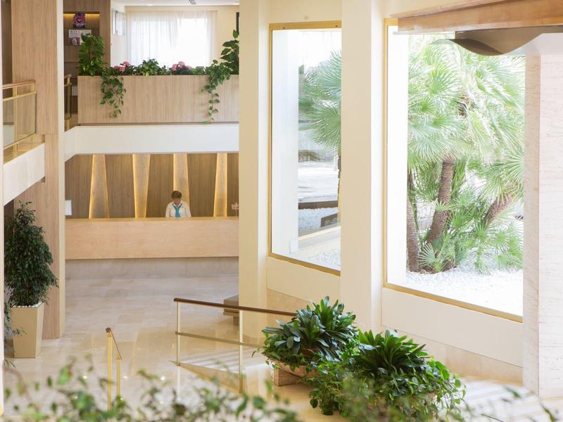 Bright, modern hotel interior with large windows and rooms with glass walls.