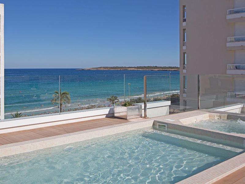 Hotel pool with a view of the blue sea under clear, sunny weather.