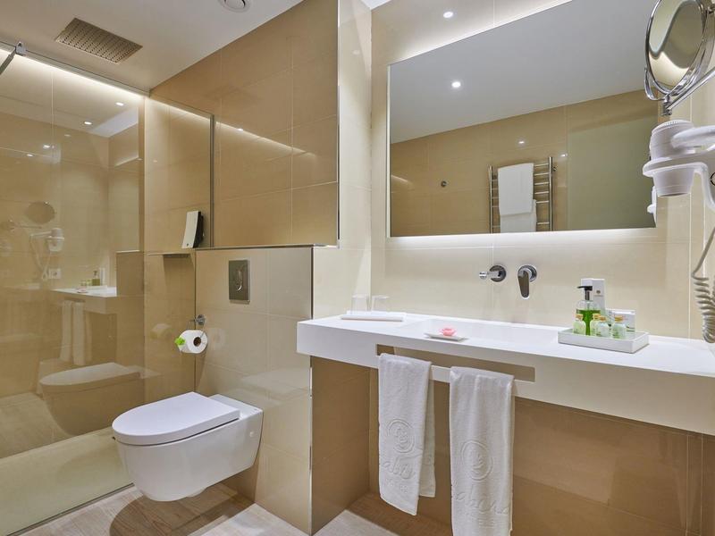 Modern hotel bathroom with shower, toilet, and spacious sink area.