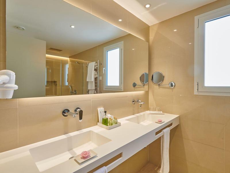 Modern hotel bathroom with two sinks, large mirror, and hairdryer.