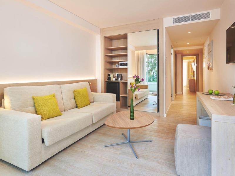 Modernly furnished hotel room with sofa, flat-screen TV, and access to a balcony.