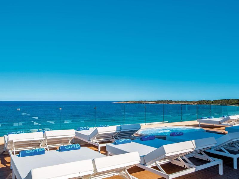 Sun loungers by the pool overlooking the blue sea and clear sky.
