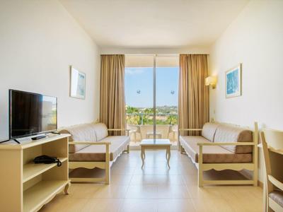 Světý obývací pokoj s dvěma pohovkami, televizí a velkým oknem s výhledem ven.