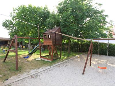 Dětské hřiště s lezeckou věží, skluzavkou, houpačkami a pískovištěm v hotelové zahradě.