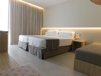 Moderní hotelový pokoj se dvěma dvojlůžky a jemným nepřímým osvětlením.