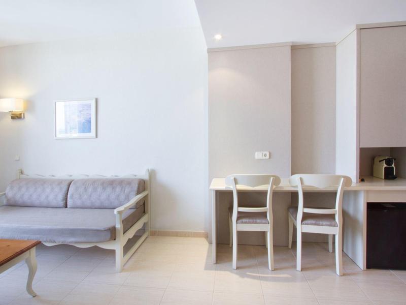 Světý pokoj s pohovkou, stolem a třemi židlemi u malého jídelního koutu.