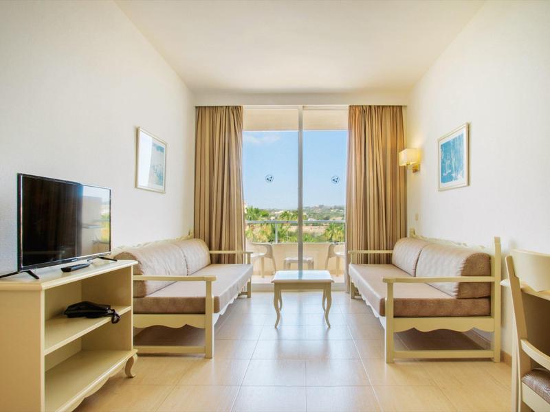 Světý obývací pokoj s dvěma pohovkami, televizí a velkým oknem s výhledem ven.