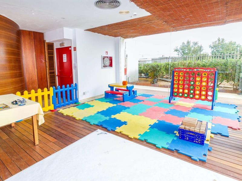 Colorful indoor play area with foam mats, small fence, and play equipment in a hotel.