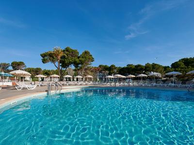 Large outdoor pool with clear water, surrounded by sun loungers and umbrellas.