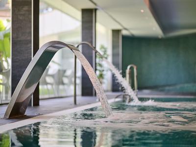 Modern indoor pool with water features and a cozy hotel setting.
