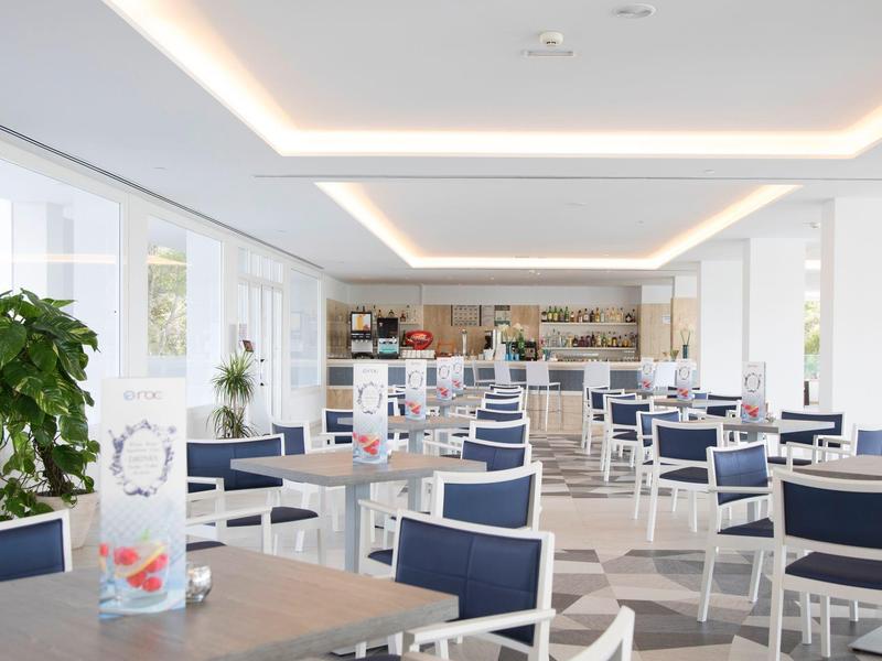 Salle à manger lumineuse et spacieuse avec des chaises bleues et blanches et de grandes fenêtres.