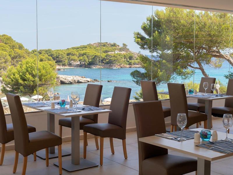 Modernes Restaurant mit Ausblick auf das Meer und grüne Hügel im Hintergrund