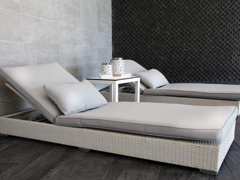 Deux lits de repos blancs modernes avec coussins et une petite table d'appoint blanche à l'intérieur.