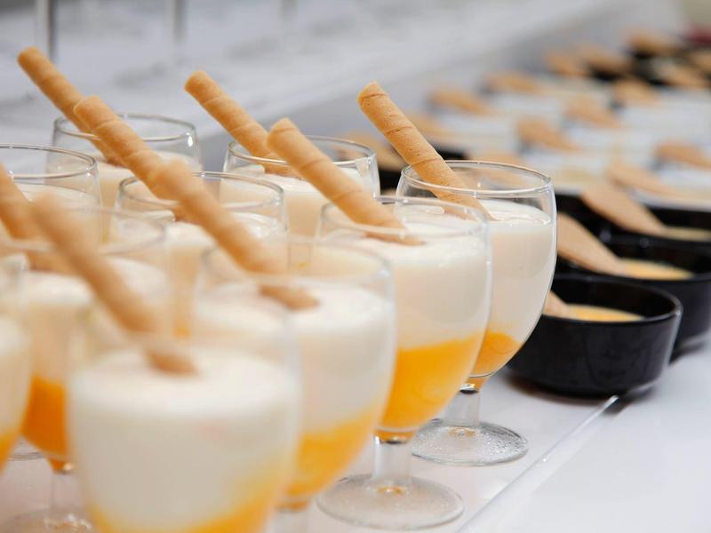 Dessert à la mangue en couches dans des verres avec des biscuits en gaufrette sur une table de buffet.