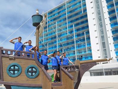 Skupina lidí pózuje na replikě lodi před vysokou hotelovou budovou.