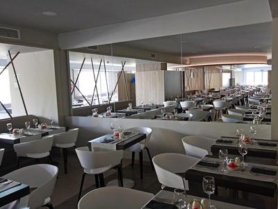 Velká moderní jídelna s bílými židlemi a prostřenými stoly.