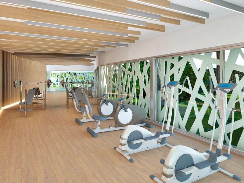 Moderní posilovna s veslovacími trenažéry, dřevěná podlaha a dostatek denního světla.
