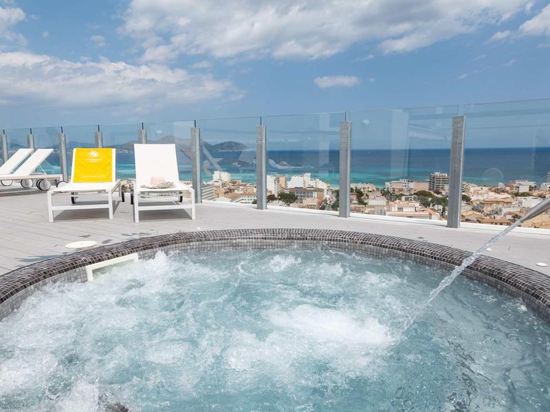 Vírivka na terase s výhledem na moře a lehátky pod zataženou oblohou.