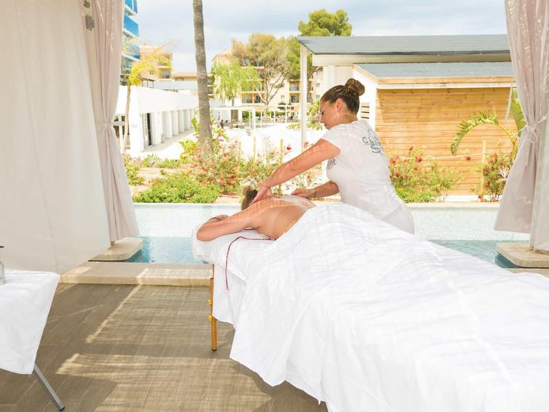 Žena dostává masáž na pohodlném stole v světlé místnosti s výhledem ven.