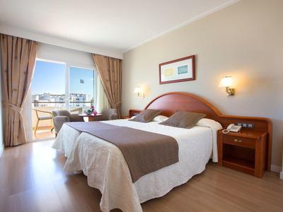 Gemütliches Hotelzimmer mit Doppelbett und Balkon mit Aussicht.