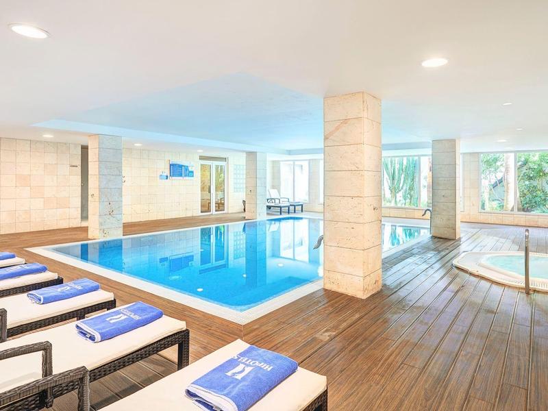 Helles Hallenbad mit Liegestühlen und großen Fenstern, die Aussicht auf Bäume bieten.