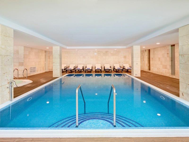 Moderner, ruhiger Innenpool mit bequemen Liegestühlen und heller Beleuchtung.