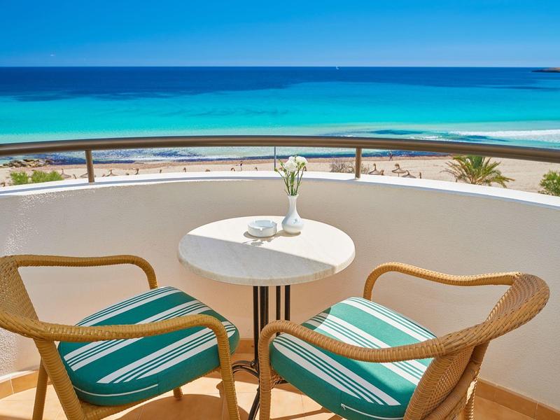 Balkon mit zwei Stühlen und Tisch mit Blick auf Meer und Strand.
