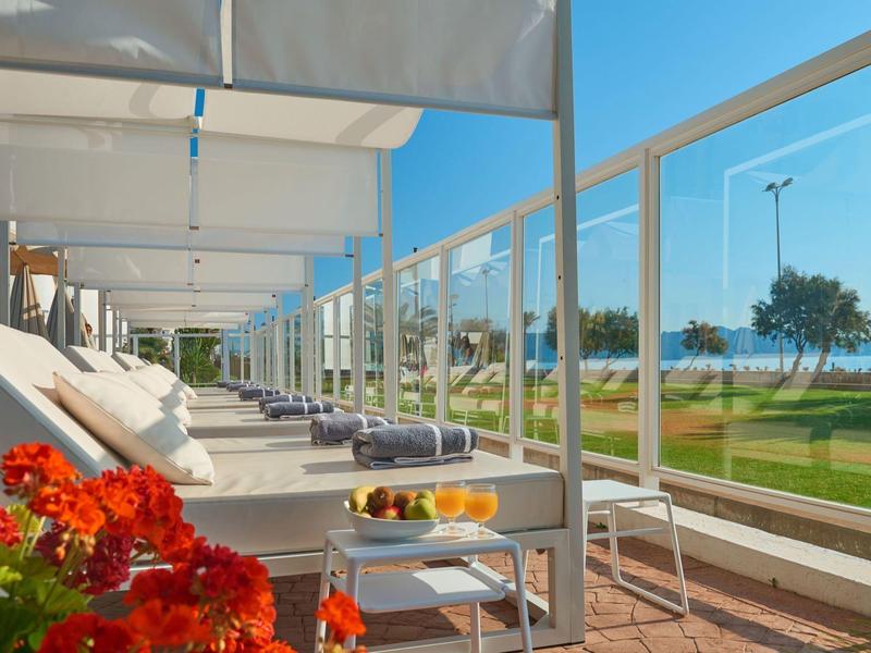 Moderne Außenterrasse mit Liegestühlen und Blick auf das Meer an einem sonnigen Tag.