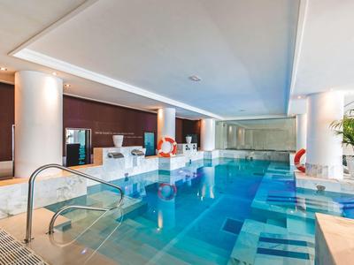 Piscine intérieure moderne dans une pièce lumineuse avec colonnes et espace détente