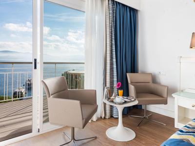 Deux fauteuils et une table sur un balcon avec vue sur la mer.