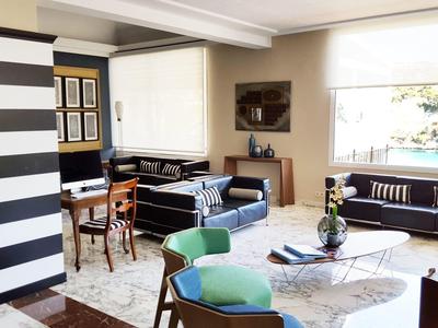 Pièce lumineuse avec mobilier moderne, pilier rayé et fenêtre donnant sur un jardin.