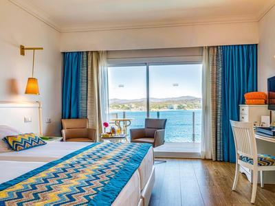 Chambre d'hôtel lumineuse avec vue sur la mer, lit double et balcon