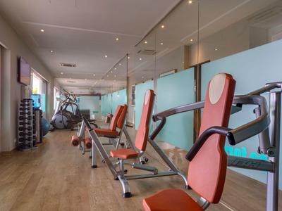 Moderner Fitnessraum mit Trainingsgeräten und großen Fenstern