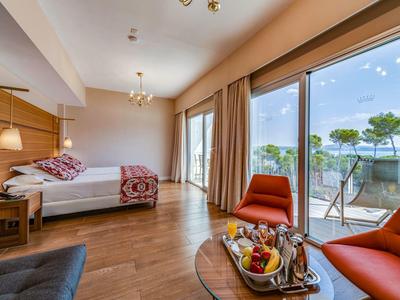 Chambre d'hôtel moderne avec lit double, parquet et balcon avec vue sur la mer.