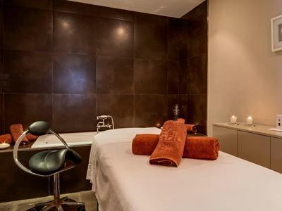 Espace bien-être confortable avec table de massage, deux serviettes orange et lumière douce.