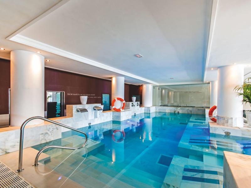 Piscine intérieure moderne dans une pièce lumineuse avec colonnes et espace détente