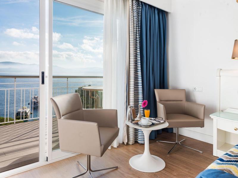 Deux fauteuils et une table sur un balcon avec vue sur la mer.