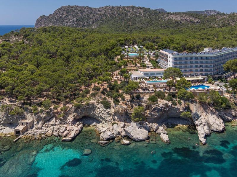 Hôtel sur une côte rocheuse avec eau claire et beaucoup de verdure.