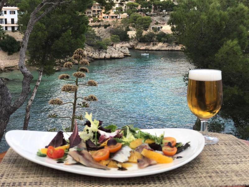 Vue sur un lac avec une assiette de nourriture et un verre de bière au premier plan.
