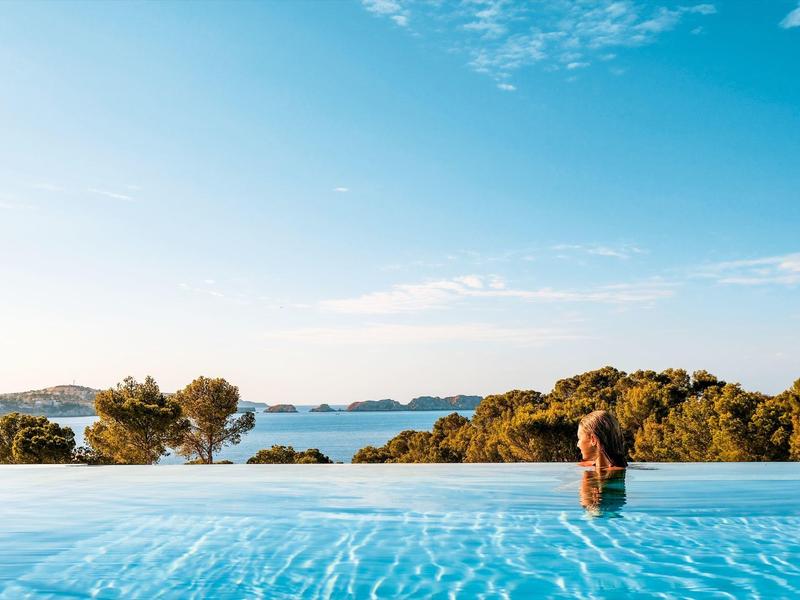 Personne se détend dans une piscine avec vue sur des arbres et un ciel clair
