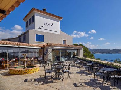 Terraza de restaurante junto al mar con mesas y sillas de metal en un día soleado