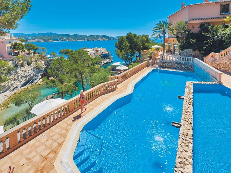 Piscina con vista al mar y vegetación circundante en un lugar de vacaciones.