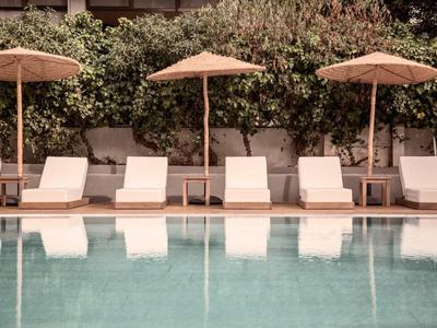 Piscina con lettini e ombrelloni davanti a una siepe verde