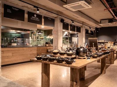 Moderner Selbstbedienungsbereich mit Holztheken, schwarzen Schüsseln und offenem Küchenbereich.